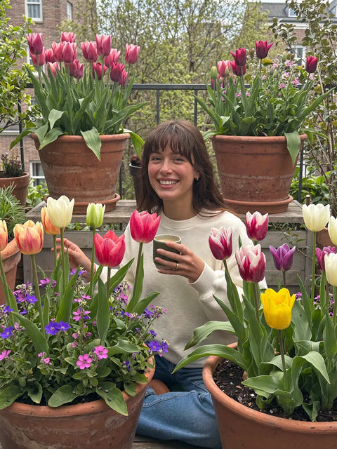 Vrouw op het balkon tussen potten met tulpen