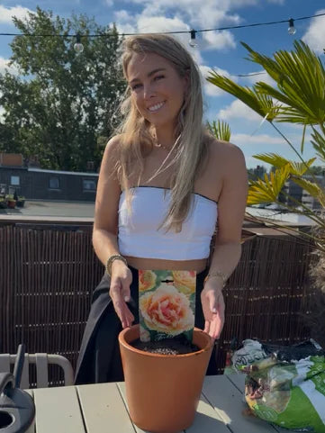 Vrouw plant bloembollen in een pot op haar dakterras